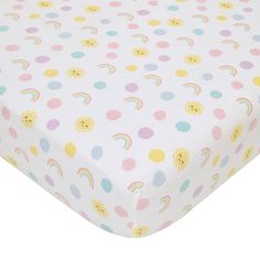 a baby crib sheet with rainbows and clouds printed on the bottom, along with polka dots