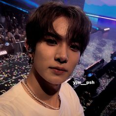 a young man wearing a white shirt standing in front of a stage with lots of confetti on it