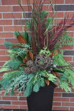 a planter filled with lots of greenery and pine cones on the side of a brick wall