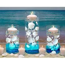 three candles are sitting on the sand near the water and beach with seashells