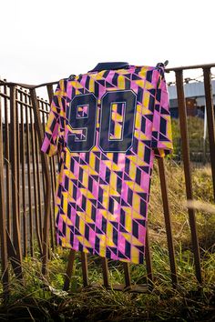 a purple and yellow jersey is hanging on a metal fence near some tall green grass