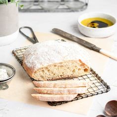 a loaf of bread sitting on top of a cooling rack next to bowls and utensils