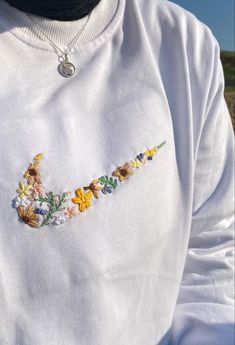 a close up of a person wearing a white shirt with embroidered flowers on the chest