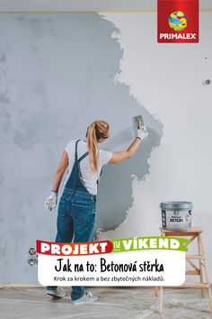 a woman in overalls painting a wall