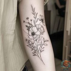 a black and white flower tattoo on the left inner arm, with flowers growing out of it