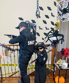 two children dressed up as police officers standing in front of a staircase decorated with halloween decorations