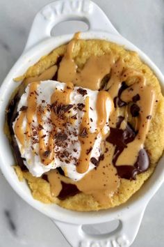 an ice cream dessert with chocolate and caramel drizzled on top in a white dish