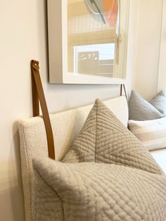 a white couch sitting next to a wall with pillows on it and a painting hanging above the couch