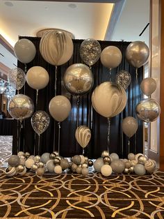 balloons and streamers are hanging from the ceiling in front of a black drape