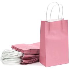 pink paper bags with white handles are stacked on top of each other