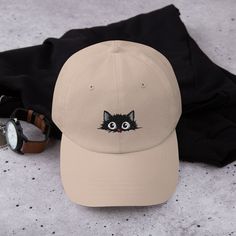 "Embroidered Black Cat Hat | Cat Lover Hat | Cat Lover Gifts | Funny Black Cat Hat | Cat Mom Gift | Baseball Cap | Hatphile Pre ** HOW TO ORDER 1. Check our photos for sizing and color options.  2. Select your size and color from the drop-down menus.  3. Click \"ADD TO CART\" to add the shirt to your cart. 4. Click \"PROCEED TO CHECKOUT\" to purchase your shirt. ** SIZE One size fit all with adjustable strap with antique buckle ** DETAILS: - 100% chino cotton twill - Green Camo color is 35% chino cotton twill, 65% polyester - Unstructured, 6-panel, low-profile - 6 embroidered eyelets - 3 ⅛\" (7.6 cm) crown - Adjustable strap with antique buckle ** CARE: - Machine wash: cold water - Air dry ** PRINTING METHOD: Embroidered printing is a captivating process that combines embroidery and printi One Size Cat Ear Hats With Cat Design, Trendy Cat Design Hats With One Size Fits Most, One Size Cat Ears Hat With Cat Design, Black Hat With Cat Ears And Cat Design, Black Cat Design Hat With Cat Ears, Black Cat Ears Hat With Cat Design, Cute Cat-ear Hat With Cat Design, Casual Cap With Cat Design, Casual Cat Design Hat, One Size Fits Most