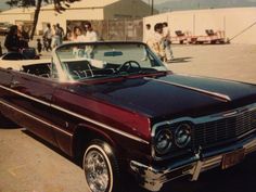 an old fashioned convertible car parked in a parking lot