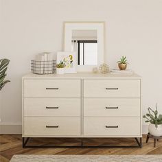 a white dresser sitting in a room next to a mirror and potted plants on top of it