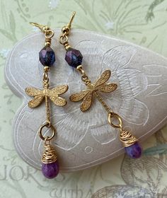 These sweet little dragonflies are solid brass. I added transparent purple Czech beads to the top and purple Czech glass teardrops wrapped in gold colored wire to the bottom. The hooks are 18k gold plated brass. Lever back hooks are available upon request. All of my earrings come on a hand stamped earring card and are lovingly wrapped in colorful tissue and placed in a drawstring bag, ready to give as a gift or keep for yourself of course! Thank you for stopping by Laura Lingle Studio! https://w Gold Dragonfly Earrings For Gift, Purple Brass Earrings As Gift, Elephant Gifts For Her, Czech Glass Jewelry, Dragonfly Gifts, Stamped Earrings, Beads Craft Jewelry, Beaded Necklace Patterns, Elephant Jewelry