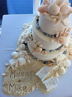 a three tiered cake with seashells and shells on it's side