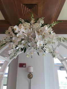 white flowers are hanging from the ceiling in a room with arched windows and wood trimmings