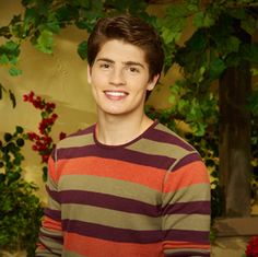 a young man standing in front of some flowers