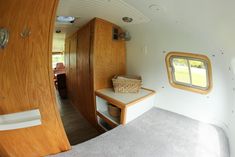 the inside of a small house with wood trimmings and white walls, including an oval window