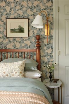 a bedroom with floral wallpaper and a wooden headboard