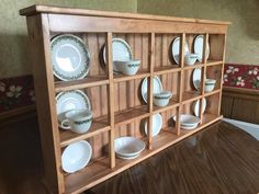 a wooden shelf with plates and cups on it's sides, against a white background