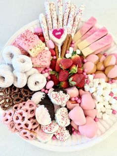 a white plate topped with lots of different types of donuts and marshmallows