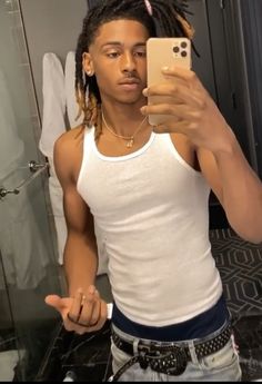 a man taking a selfie in the bathroom with his cell phone and dreadlocks