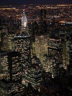 an aerial view of the city at night with skyscrapers lit up and lights on