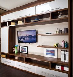 a flat screen tv sitting on top of a white entertainment center next to a window