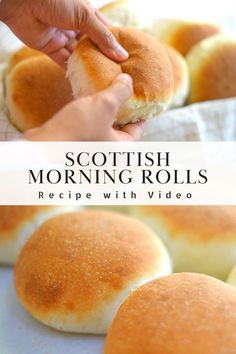 a person holding a piece of bread in front of other rolls on a table with text overlay that reads scottish morning rolls recipe with video