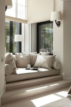 a living room filled with lots of furniture next to large windows on the side of a wall