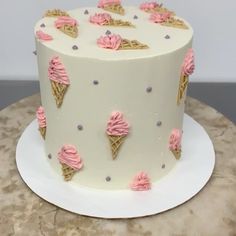 a white cake with pink frosting and ice cream cones