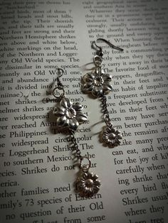 Silver flowers on a chain. Adds a touch of elegance to any outfit! Sitting at about two inches long, and set on fishhook earring backs. Adjustable Dangle Earrings With Flower Charm, Vintage Flower Charm Dangle Earrings, Vintage Dangle Earrings With Flower Charm, Elegant Metal Flower Charm Earrings, Metal Flower Charm Drop Earrings, Metal Drop Earrings With Flower Charm, Vintage Metal Flower Earrings, Vintage Metal Dangle Flower Earrings, Metal Pierced Flower Earrings