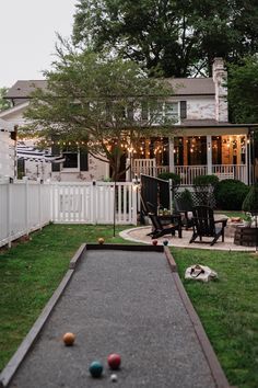 a backyard with lawn furniture and bowling balls on the ground in front of a house