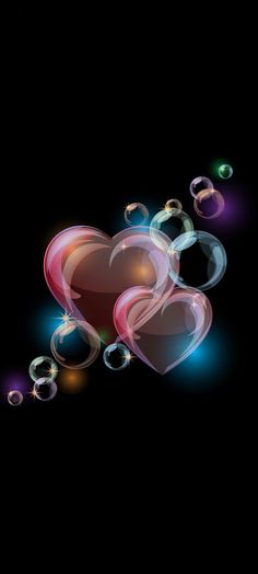 two heart shaped soap bubbles floating in the air on a black background with light effects