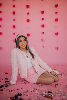 a woman is sitting on the ground with confetti all over her head and wearing a pink jacket