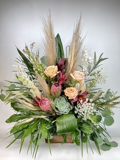 an arrangement of flowers and greenery in a wooden box