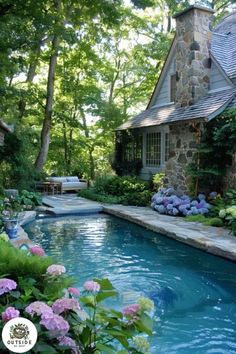 an outdoor swimming pool surrounded by flowers and greenery with a stone house in the background