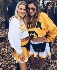 two young women standing next to each other in front of trees and leaves with their arms around each other