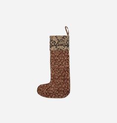 a christmas stocking hanging from the side on a white wall with a brown and black pattern