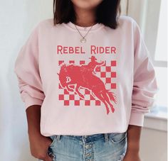 The distressed rebel rider makes a trendy western sweatshirt.    GILDAN 18000 UNISEX SWEATSHIRT  *50% cotton, 50% polyester *Machine wash in cold with similar colors, tumble-dry on low *Loose fit, runs true to size, ribbed crewneck collar *Size up for oversized look SIZES (See the size chart in the photos)    S:    20" width, 27" length, 33" sleeve    M:  22" width, 28" length, 34" sleeve    L:    24" width, 29" length, 35" sleeve    XL:  26" width, 30" length, 36" sleeve   2XL: 28" width, 31" length, 37" sleeve   3XL: 30" width, 32" length, 38" sleeve   4XL: 32" width, 33" length, 39" sleeve   5XL: 34" width, 34" length, 40" sleeve PROCESSING  *2-5 business days, usually sooner * Order before December 8th for delivery by Christmas SHIPPING  *FREE within the US for orders over $35 *3-7 bus Cowgirl Disco, Western Sweatshirts, Country Girl Shirts, Cowboy Aesthetic, Space Cowgirl, Disco Cowgirl, Western Graphic Tees, Western Aesthetic, Girl Shirt