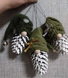 three small pine cones are hanging from a string with bells on them, and one is made out of yarn