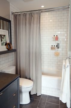 a white toilet sitting next to a bath tub in a bathroom on top of a tiled floor