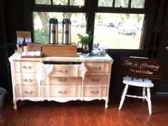 an old dresser is painted white and has coffee on it, along with other items