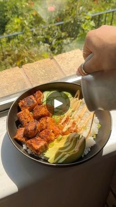 someone is pouring sauce on some food in a bowl with vegetables and meats inside