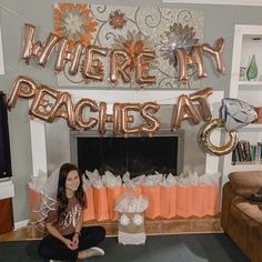 a woman sitting on the floor in front of a fireplace with balloons that say where my peaches at