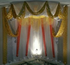 a stage set up with gold and red draping on the curtain, white walls and black carpet