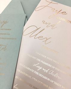 two folded wedding programs with gold foil on the front and back, sitting next to each other