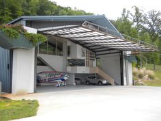 a car is parked in front of a garage with a boat on the ramp next to it