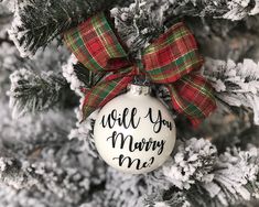 a christmas ornament that says will you marry me? hanging on a tree