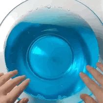 two hands reaching into a blue bowl with water in it and another hand reaching out to the bowl